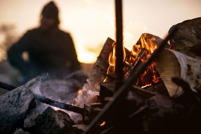 Cozy campfire at dusk with a person in soft focus in the background